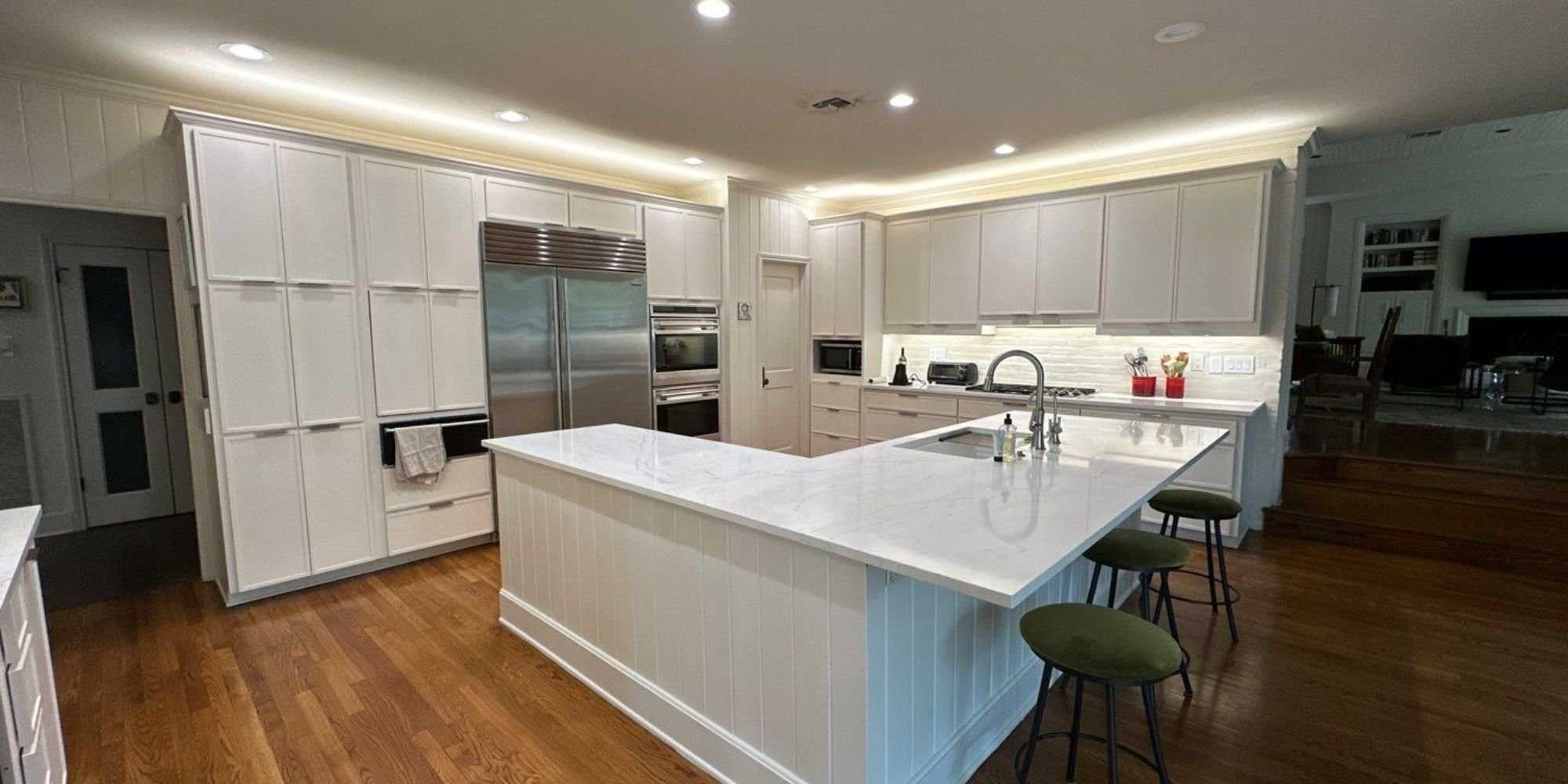 Modern San Antonio kitchen remodel with white cabinets, marble countertops, stainless steel appliances, and spacious island