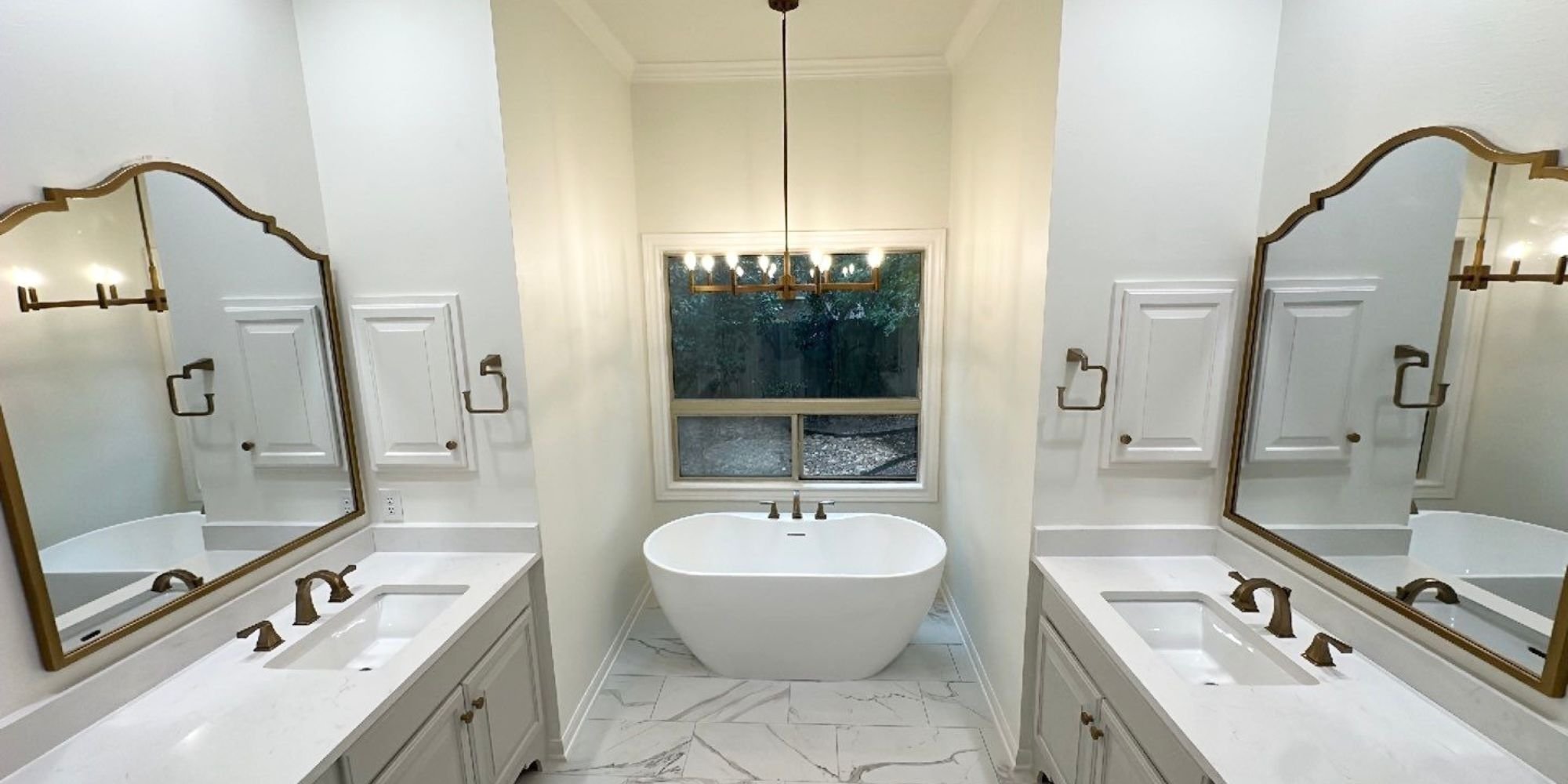 Classic bathroom design with soaking tub between twin sinks and natural light in San Antonio