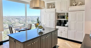 Bright San Antonio kitchen with custom white cabinetry, black countertops, and expansive windows by Wade Caldwell Construction