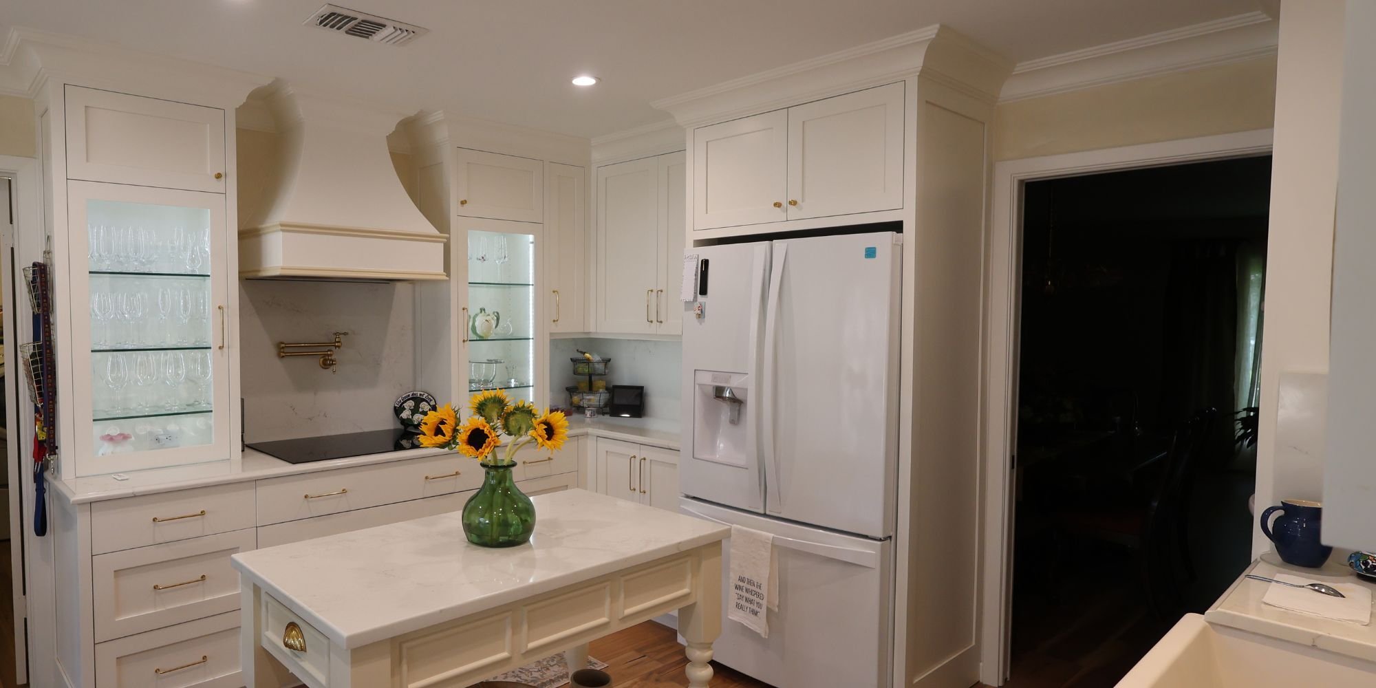 Bright white kitchen remodel in San Antonio by Wade Caldwell Construction with custom cabinets and glass display shelving