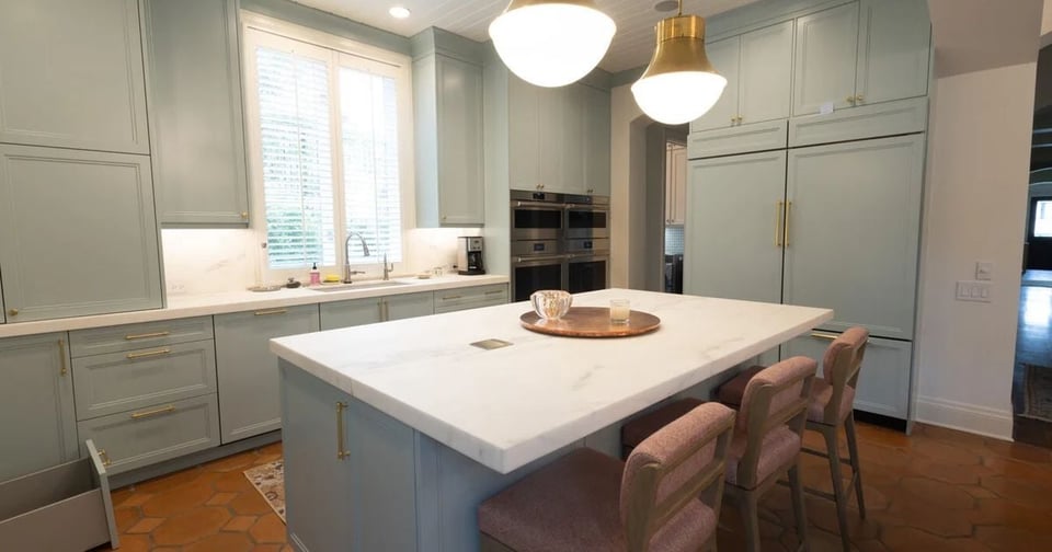 Light sage green cabinetry and oversized marble island in a San Antonio kitchen remodel by Wade Caldwell Constructio