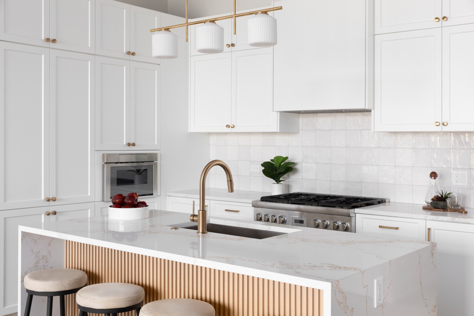 All-white kitchen remodel with gold fixtures and fluted island by Wade Caldwell Construction in Castle Hills, TX