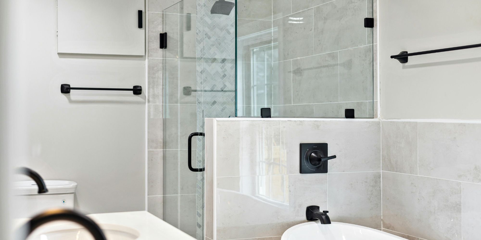 Sleek bathroom renovation in San Antonio by Wade Caldwell with soaking tub, frameless glass shower, and contemporary black