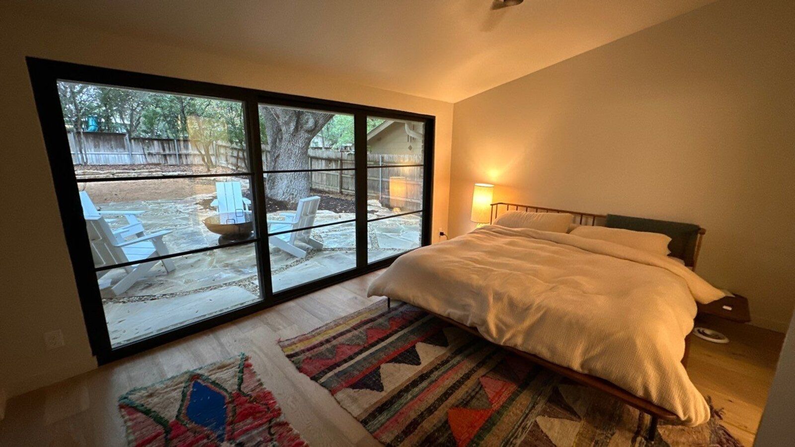 Peaceful bedroom with modern furnishings and sliding glass doors leading to stone pati