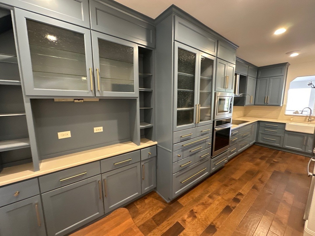 Full kitchen remodel in Alamo Heights, TX by Wade Caldwell Construction with blue cabinetry and glass-front storage